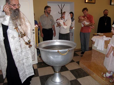 The font, the censing, and godparents holding the infants before the baptism begins, 2010