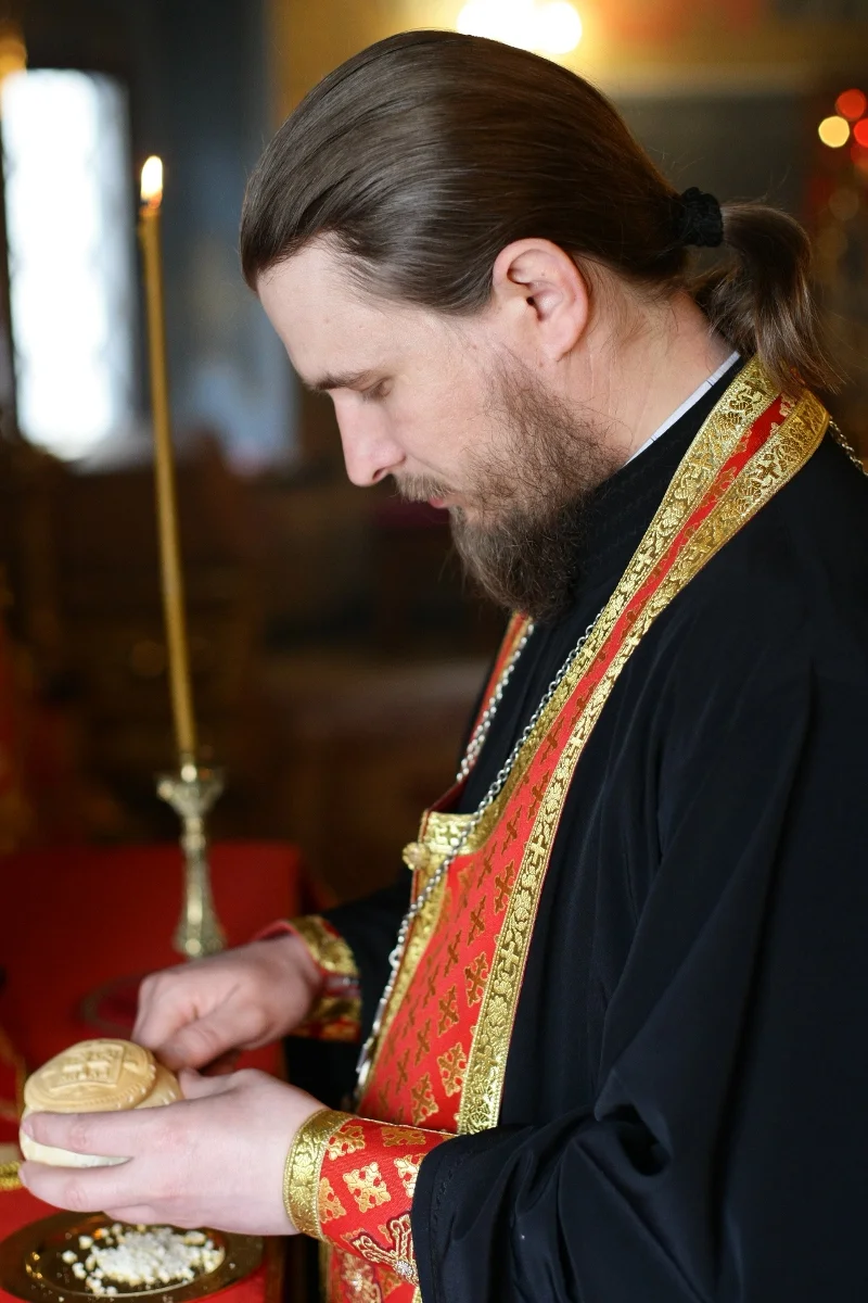 The priest holds a prosphora with the seal; the particles already taken out lie below