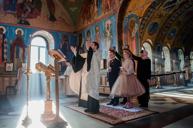 The crowns are held over the heads of bride and groom. Dormition church in Voronezh, 2019