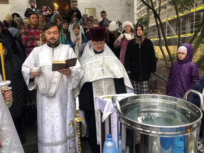 Сосуд с водой, книга и люди с бутылями в очереди за освящённой водой. Кёльн, январь 2026