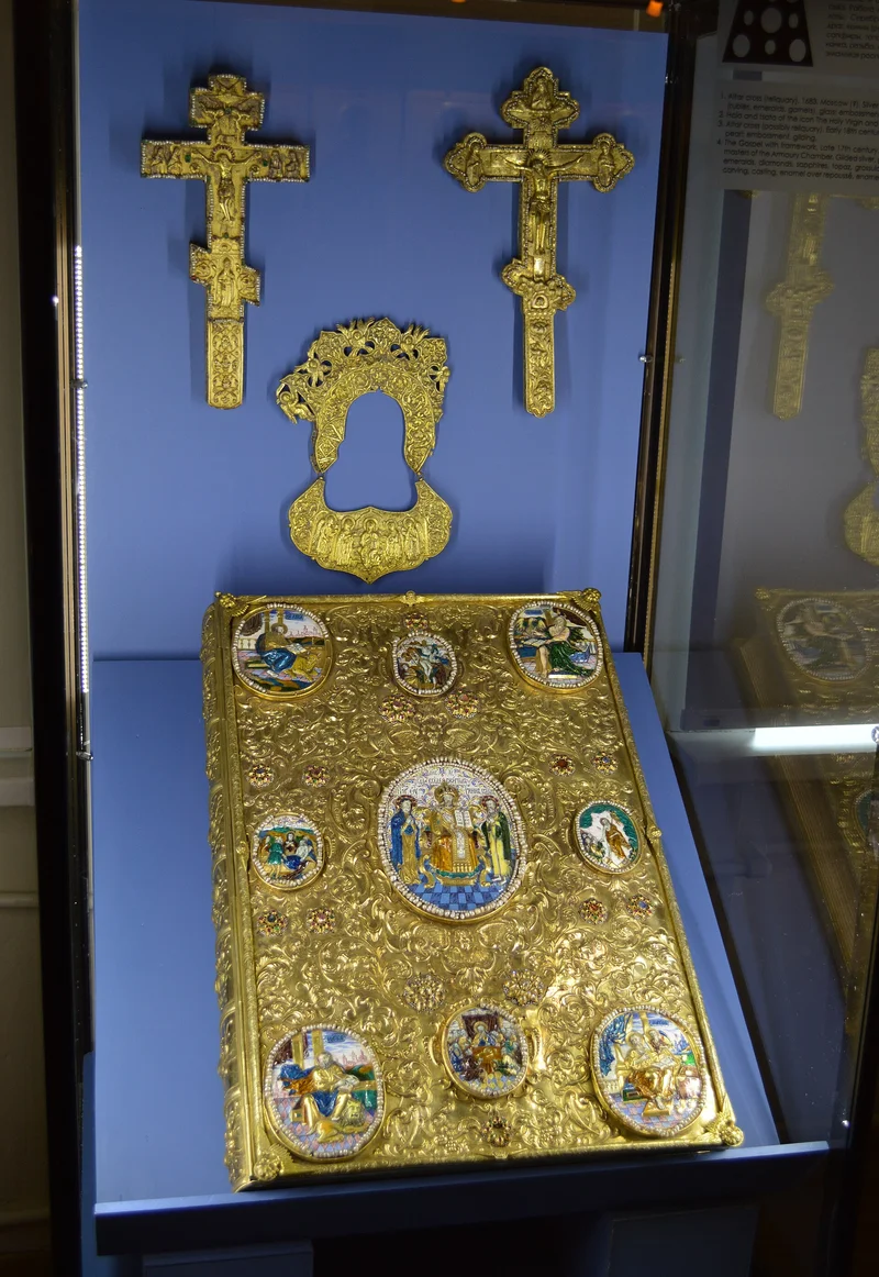 A late-17th-century Gospel cover with enamel medallions at the corners, beside two altar crosses. Pskov Museum