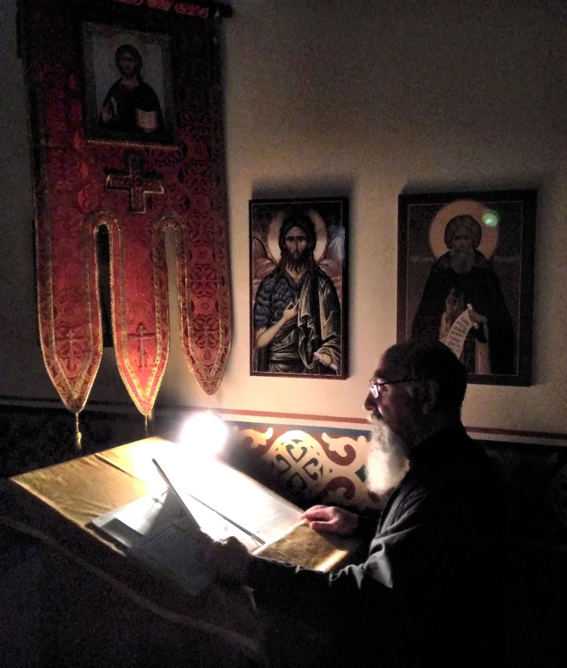 A reader at the analogion reading by lamplight; evening service, Ottawa, 2017