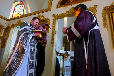 Priest and deacon in black in the dim church. Russian parish in Düsseldorf, 1 March 2017