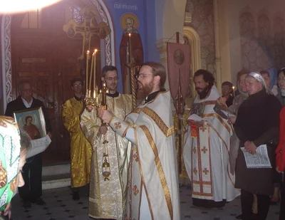 Clergy in bright vestments with candles before the procession sets out