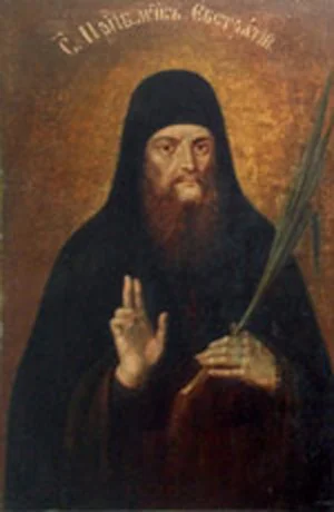 Тёмная монашеская фигура в куколе с пальмовой ветвью (символ мученичества), надпись частично разборчива